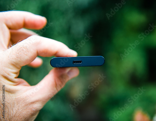 Man hand holding portable SSD 2 tb external hard drive disk with high read and write speed against green background unboxing testing - looking at usb-c thunderbolt connection