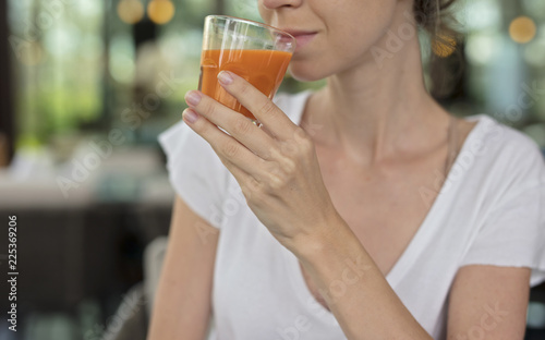 Happy smiling woman drinking carrot juice close up. Healthy eating and lifestyle concept