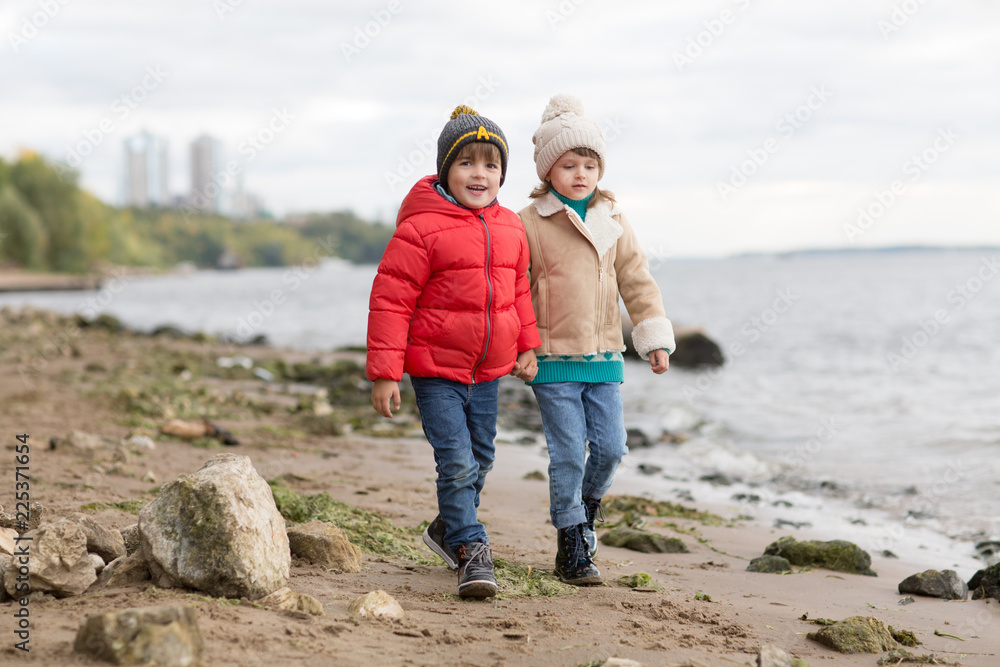 Two little children boy and girl playing and  having fun together autumn outdoors