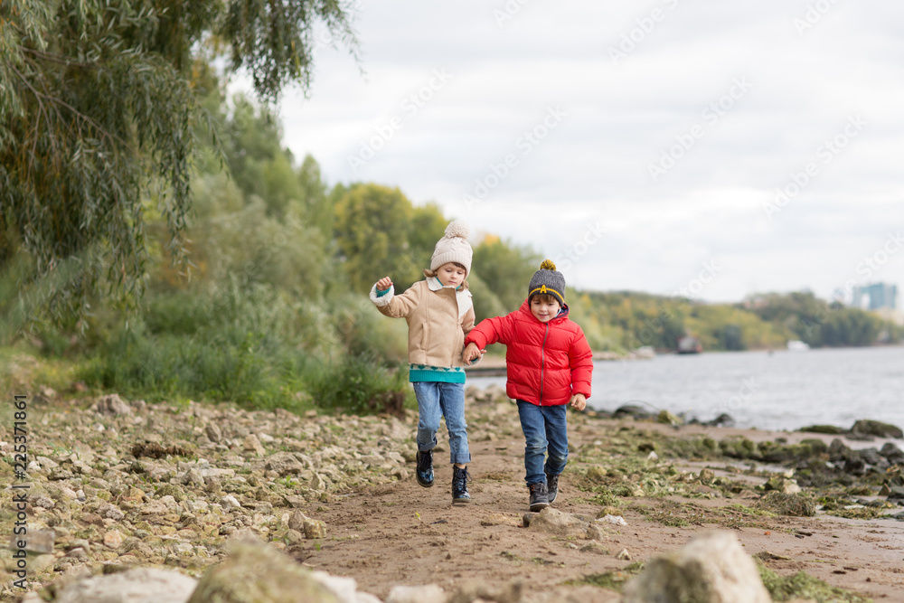 Two little children boy and girl playing and  having fun together autumn outdoors