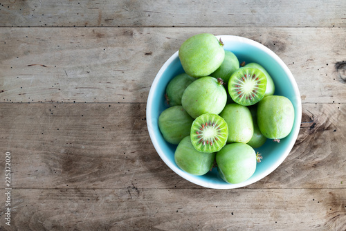 hardy kiwi fruits or kiwi berry actinidia arguta in ceramic bowl on wooden kitchen table