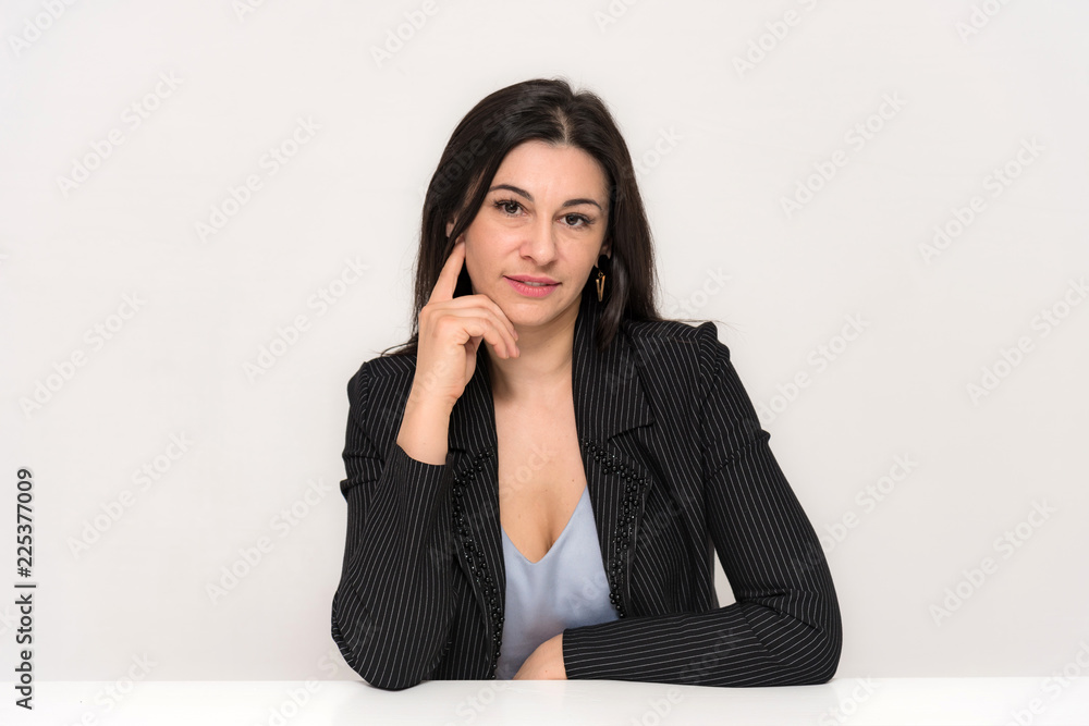 Portrait of a beautiful brunette woman on a white background with different emotions sitting at the table. Portrait of a beautiful brunette woman on a white background with different emotions sitting at the table.