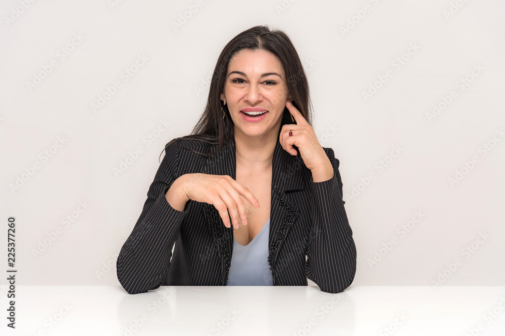 Portrait of a beautiful brunette woman on a white background with different emotions sitting at the table. Portrait of a beautiful brunette woman on a white background with different emotions sitting at the table.