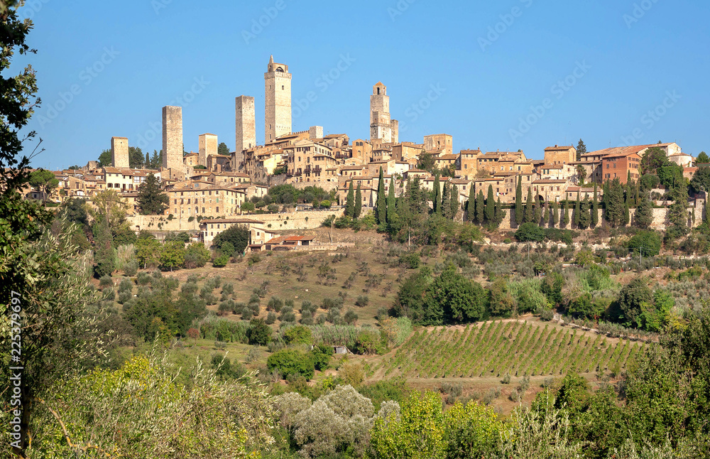 Towers and traditional brick houses of ancient Tuscan town at sunny day. Historic San Gimignano town. UNESCO World Heritage Site