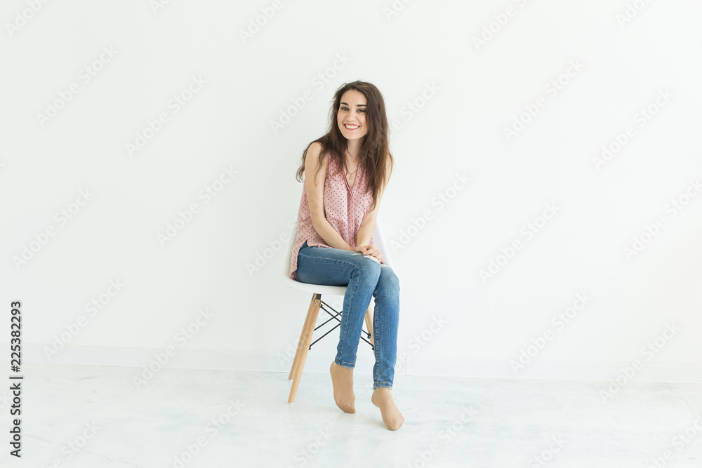 Young lady sitting on chair in white background with copy space Young lady sitting on chair in white background with copy space