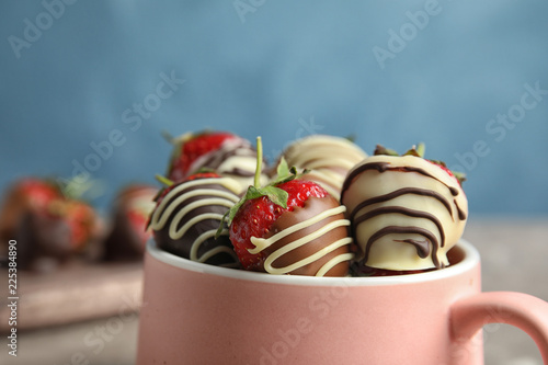 Cup with chocolate covered strawberries on table, closeup