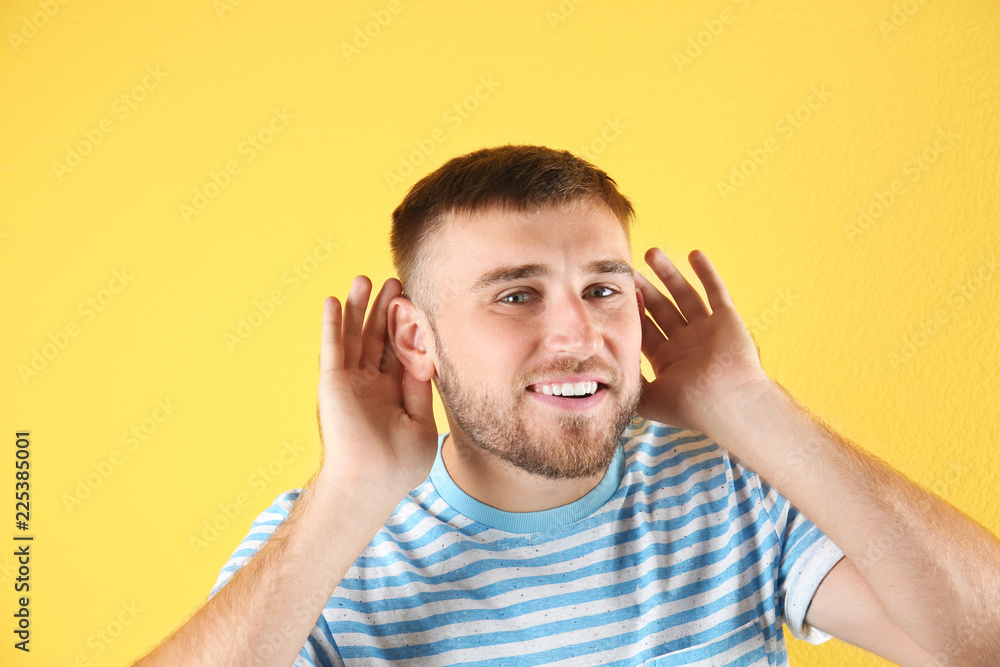 Young man with hearing problem on color background Young man with hearing problem on color background