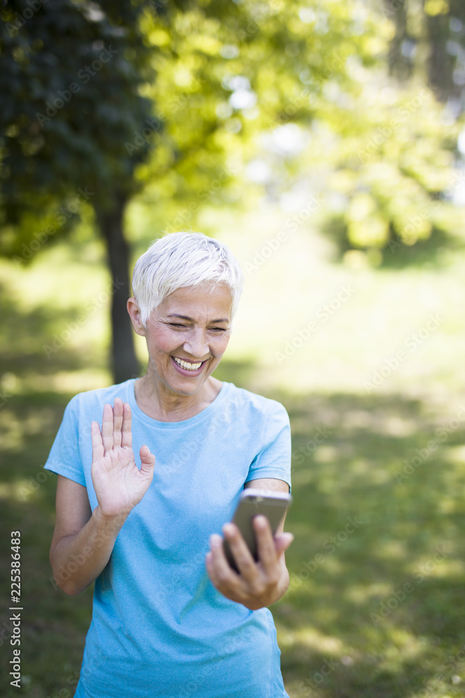 Sporty senior woman using mobile phone in the park Sporty senior woman using mobile phone in the park