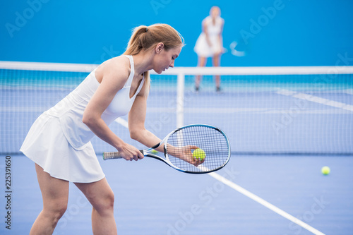 Obraz na plátně Side view portrait of young sportswoman ready to serve ball while playing tennis