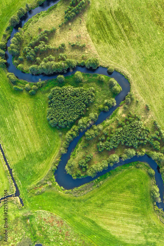 Aerial view on winding river in green field