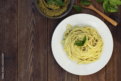 Italian traditional spaghetti with basil pesto pasta with cheese, pine nuts, olive oil, rustic table. Copy space. photo