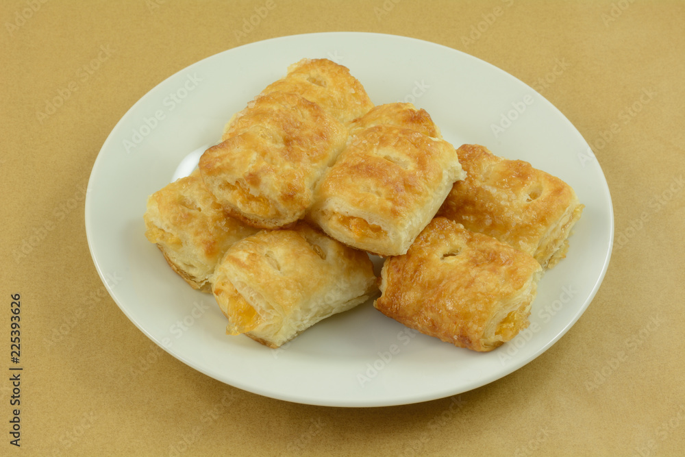 Stack of mini apple breakfast turnovers on white plate on table Stack of mini apple breakfast turnovers on white plate on table