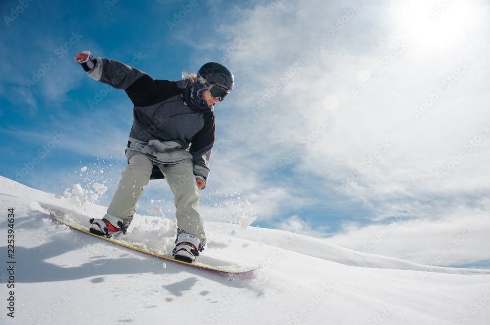 Young female snowboarder running down the mountain slope - obrazy, fototapety, plakaty 