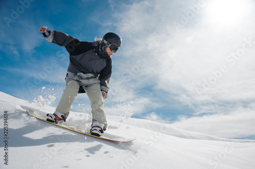 Young female snowboarder running down the mountain slope photo