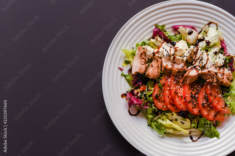 Meat salad with tomato served in white plate on dark table. Copy space Meat salad with tomato served in white plate on dark table. Copy space