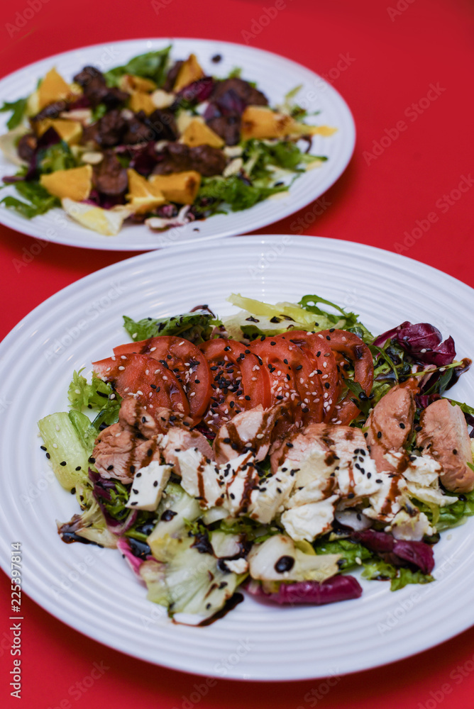 Meat salad with tomato served in white plate on dark table. Copy space