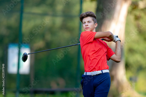 Young golf player hits a driver shot from the tee on a golf course. Concept: competition, concentration, sport, wealthy life.