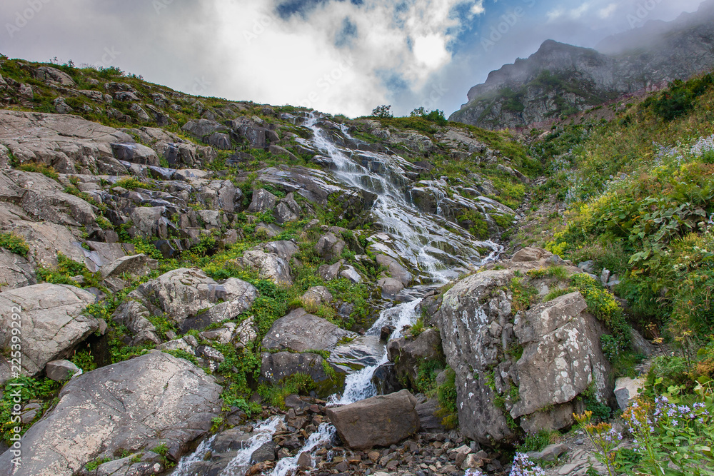 Caucasus mountain waterfall on rock mountain in the green rocky mountainside. Caucasus mountain waterfall on rock mountain in the green rocky mountainside.