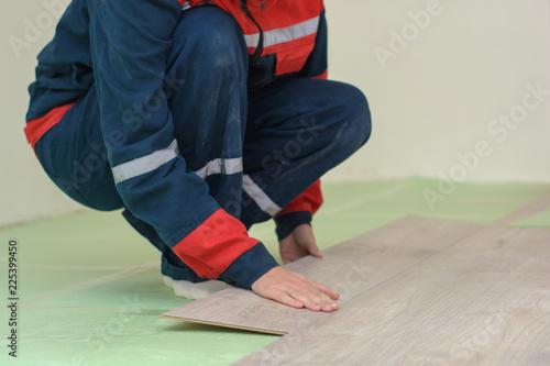 Happy young woman measuring and marking laminate floor tile, installing laminate flooring. Close-up photo with focus on her hands. Home improvement and renovation concept