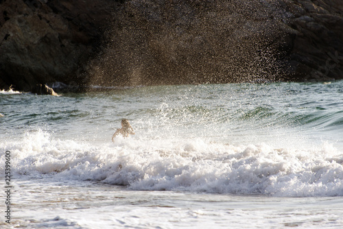 People palying, swimming in the waves in the island of Patmos, Greece in summer time