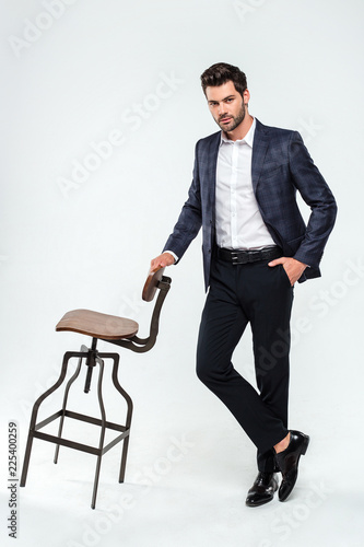 Well dressed and confident. Full length of handsome young man looking at camera while standing against white background