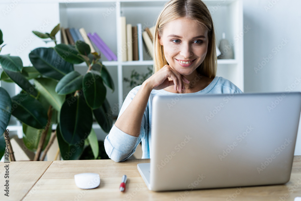 New solution every day. Confident young woman in smart casual wear working on laptop while sitting at her working place in office. New solution every day. Confident young woman in smart casual wear working on laptop while sitting at her working place in office.