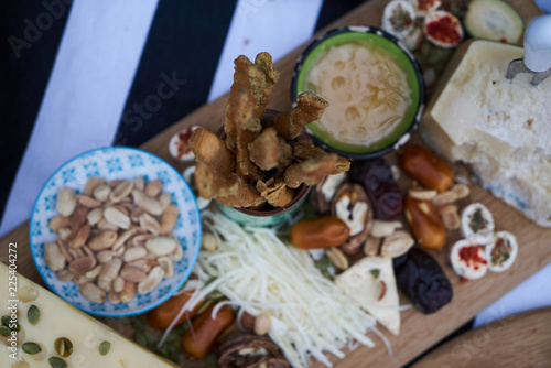 Snacks for beer with different food, top view. Salty and cheese bar of several kinds of cheese, grapes, olives, nuts, fruits decorated on table. Holiday party outdoors, picnic