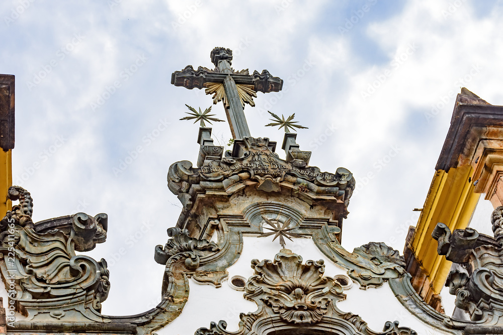 Baroque style crucifix on top of ancient and historical church in the city of Sabara in Minas Gerais