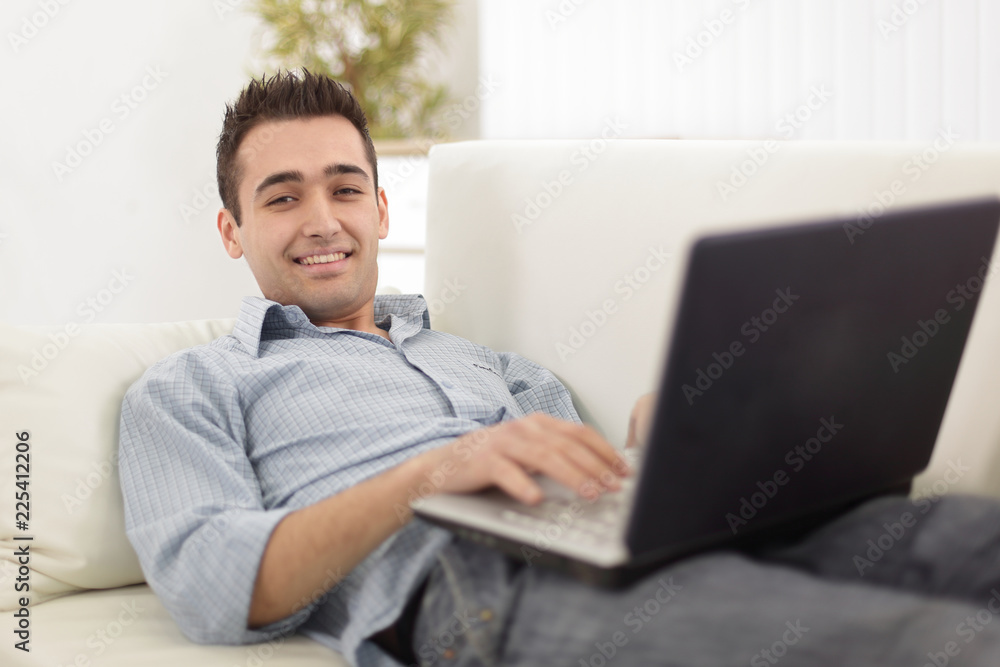 Young, handsome man using laptop sitting on sofa Young, handsome man using laptop sitting on sofa
