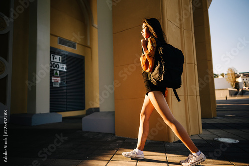 Asian beautiful woman with black hair, yellow shirt, black shorts, outdoor resting, looking at camera. Portrait young girl in an urban environment.