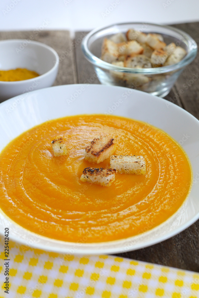 Pumpkin soup in a white plate with croutons and curry seasoning Pumpkin soup in a white plate with croutons and curry seasoning
