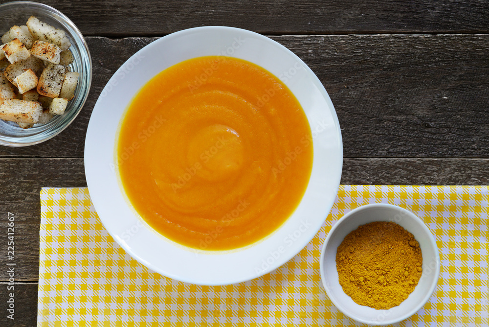 Pumpkin soup in a white plate with croutons and curry seasoning Pumpkin soup in a white plate with croutons and curry seasoning