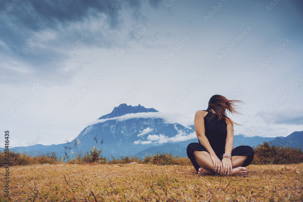 Woman sitting and playfully swinging her hair with Mount Kinabalu view in the background. Woman sitting and playfully swinging her hair with Mount Kinabalu view in the background.