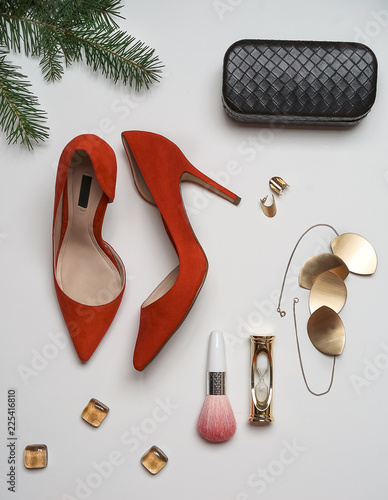 Top view to new year and christmas party outfit composition red shoes accessories jewelry clutch fir tree with balls white background. Party date night conception. Flat lay, copy space