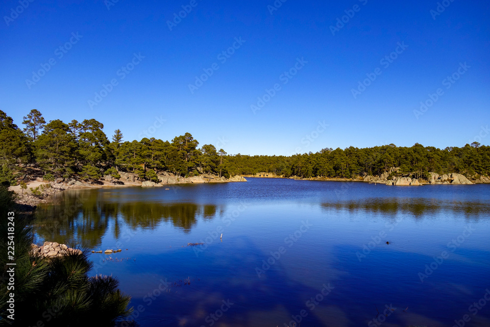 Deep crystal blue waters of Lake Arareco, surrounded by coniferous pine forest and strange rock formations near Creel in Chihuahua state of northern Mexico