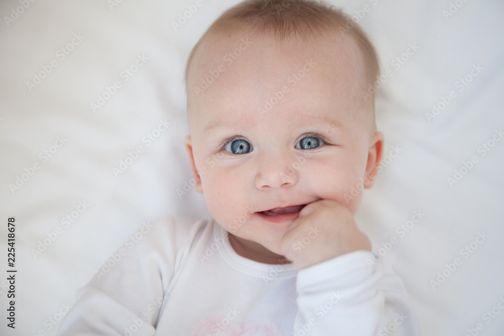 happy smiling child lies on his back on a white sheet