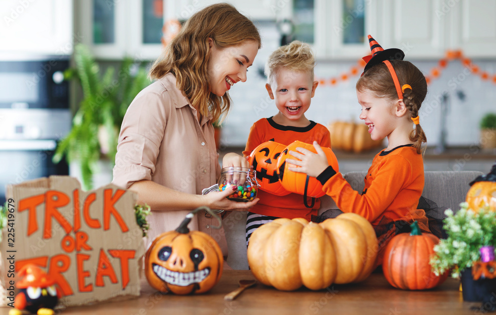 Fototapeta premium happy Halloween! mother treats children with candy at home