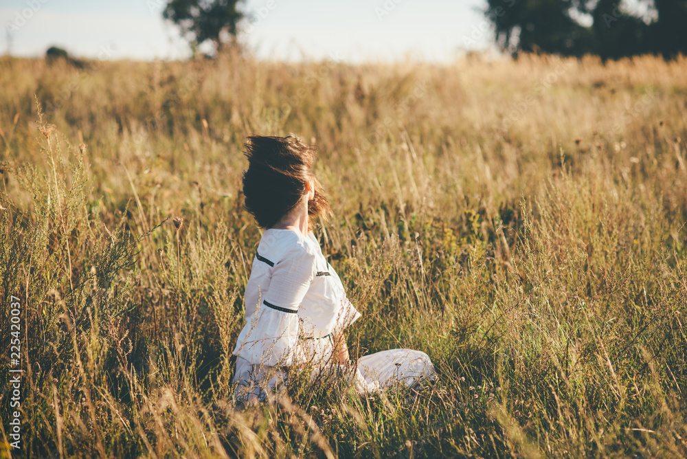 young girl is sitting on the grass wind hair young girl is sitting on the grass wind hair