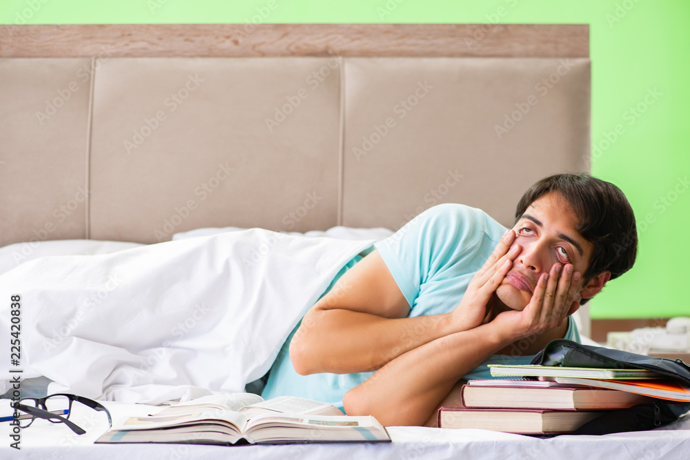 Student preparing for exams at home in bedroom lying on the bed Student preparing for exams at home in bedroom lying on the bed