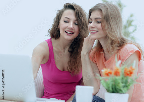 two young women discuss the video with laptop sitting at a coffe