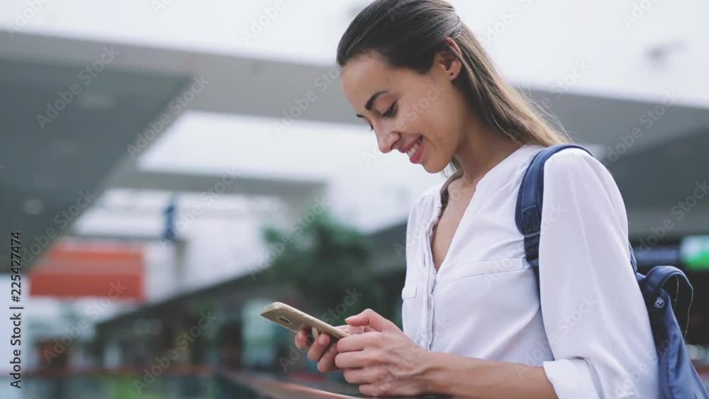 closeup of beautiful young happy caucasian woman with smartphone texting messenger inside the mall closeup of beautiful young happy caucasian woman with smartphone texting messenger inside the mall