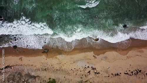 Aerial top down perspective of ocean waves on a rocky sandy shore photo