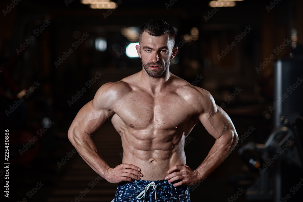 Athletic man with a muscular body poses in the gym, showing off his muscles. The concept of a healthy lifestyle