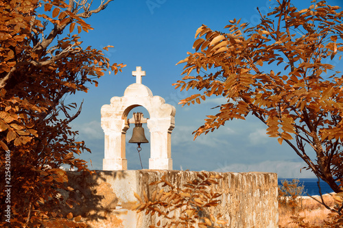 Medieval bellfry with bell surrounded by orange Autumn leaves in Rethymno, Crete photo