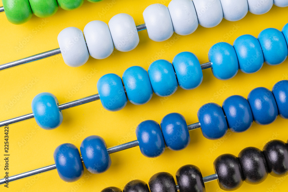 Colorful wooden abacus beads on yellow background, business financial or accounting cost and expense calculation concept, or use in education school arithmetic symbol Colorful wooden abacus beads on yellow background, business financial or accounting cost and expense calculation concept, or use in education school arithmetic symbol