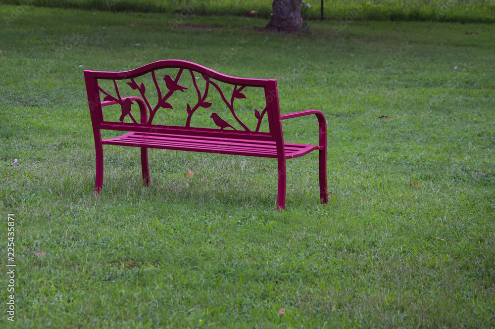 A red park bench on a green lawn on a nice day A red park bench on a green lawn on a nice day