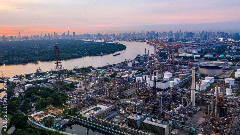 Fototapeta premium Aerial view petrochemical industrial oil refinery at sunset with city background.
