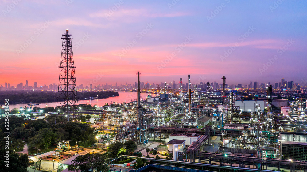 Aerial view petrochemical industrial oil refinery at sunset with city background.