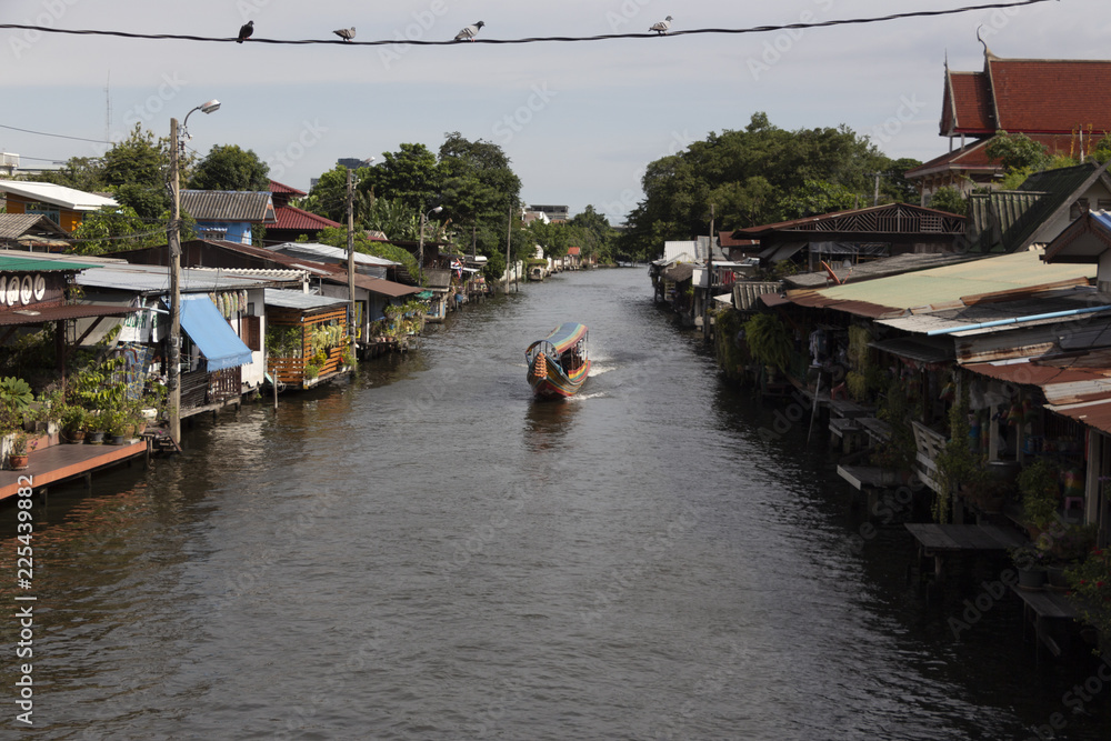 A motorboat is sailing in a canal in Bangkok, the capital of Thailand