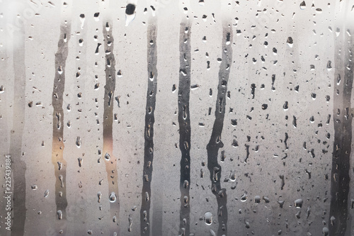 Wet, steamy glass windows with gray steam and water droplets as background
